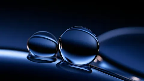 Two clear glass spheres rest on a dark blue reflective surface.