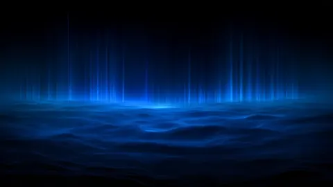 Thin cyan light pillars rise above a calm, misty blue sea under a dark sky.