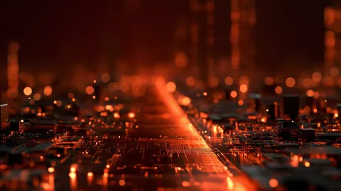 Desktop wallpaper of an orange circuit board path fading into glowing bokeh.