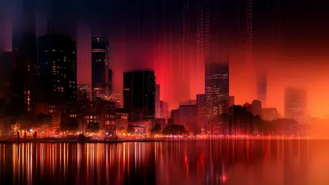 A red-lit city skyline reflects in the water, with vertical streams of light falling behind the towers.