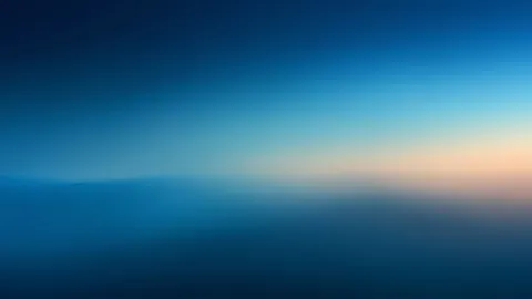 A soft gradient blends deep blue into a pale peach glow along a blurred horizon.