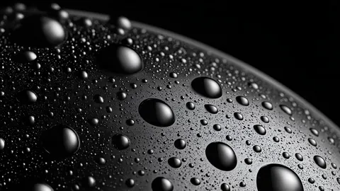 Water beads of every size cover the curved surface of a dark sphere, shining like small planets.