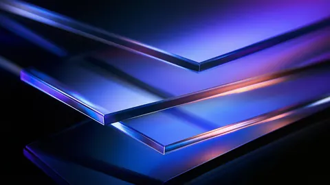 Thin sheets of sapphire glass layer at an angle, their edges catching violet and blue light.