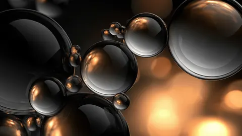 Mirror-like silver spheres cluster together against warm golden bokeh.