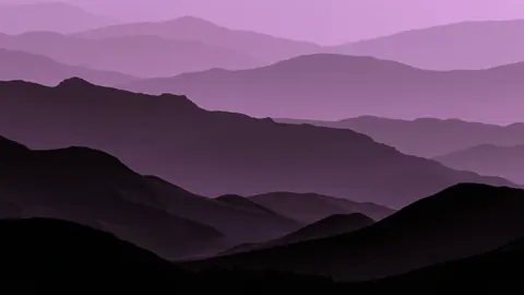 Layers of purple mountain silhouettes fade into a soft lilac sky.